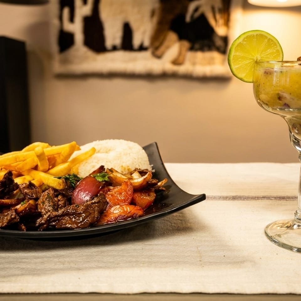Peruvian Lomo Saltado with fries and rice, alongside a passion fruit pisco sour with shrimp.